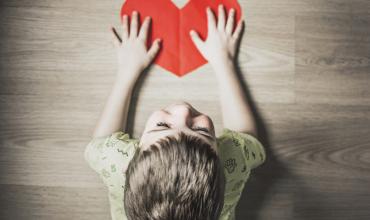 child with a red paper heart