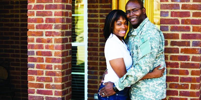 A military couple embracing outside a home