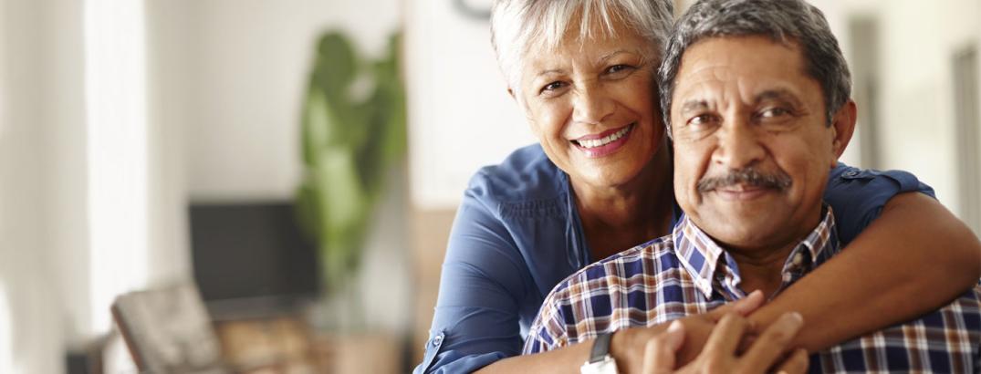 an elderly couple embracing and smiling