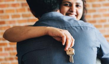 a woman holding a house key hugging a man