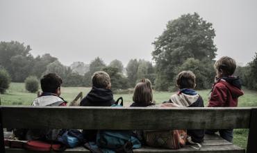 Four children sitting on a bench with their backs to the photographer