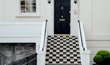 A black house door above a checkerboard staircase