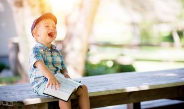 a boy laughing on a bench