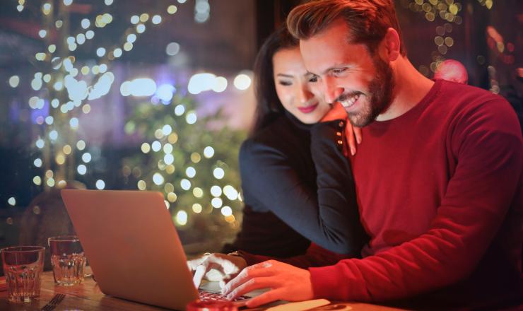 Couple looking at computer screen, with Christmas tree in background