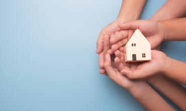 Hands holding up a little house