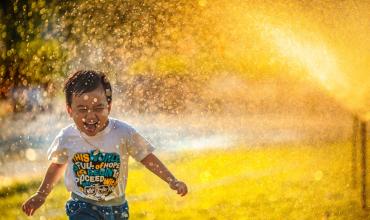 a kid running through a sprinkler