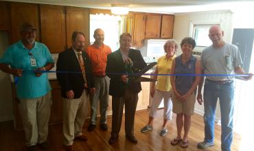 Ribbon-Cutting Ceremony Held for Disaster Recovery Property in Fair Bluff group of people around a ribbon getting ready to cut it inside a home