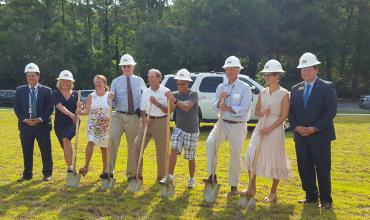 People in hard hats participating in a ground breaking ceremony