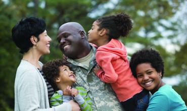 a veteran in uniform hugging his family