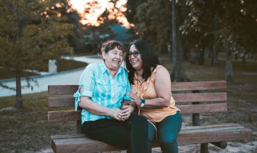 Two women laughing while sitting on a bench