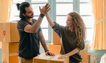 New homeowners high fiving amongst boxes in their new home