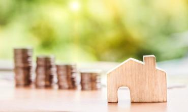 Little wooden house with coins in background