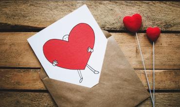 A card with a heart on it laying on a wood floor