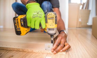 Guy drilling a hole into hardwood floor