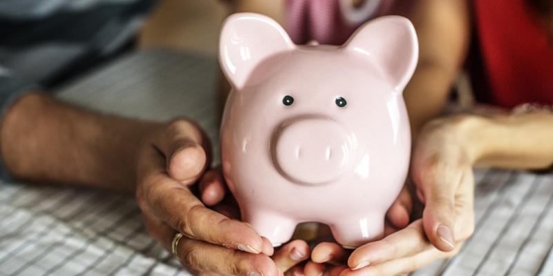 The Beginner’s Guide to Creating a Household Budget Two hands holding a piggy bank