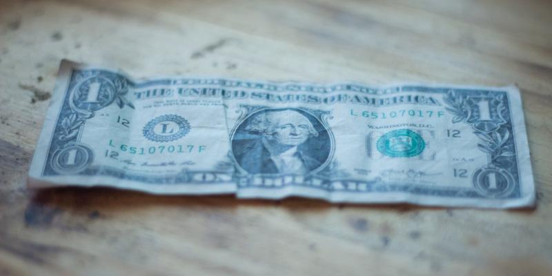 a one dollar bill on a wooden table