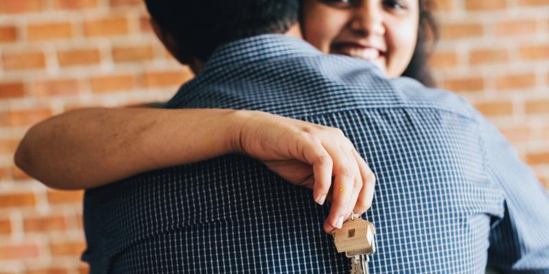 a woman holding a house key hugging a man