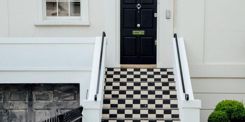 A black house door above a checkerboard staircase