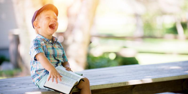 a boy laughing on a bench