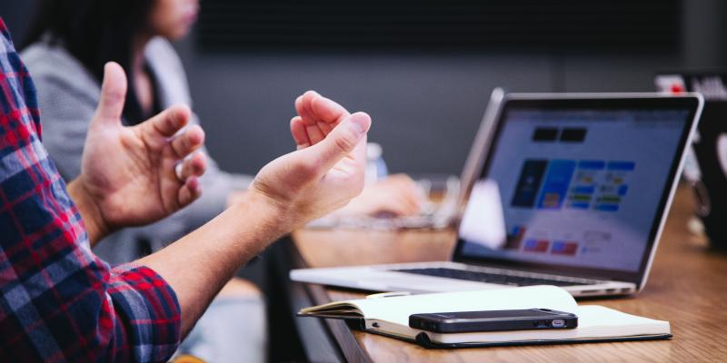 People sitting at a desk looking at a computer and talking with their hands