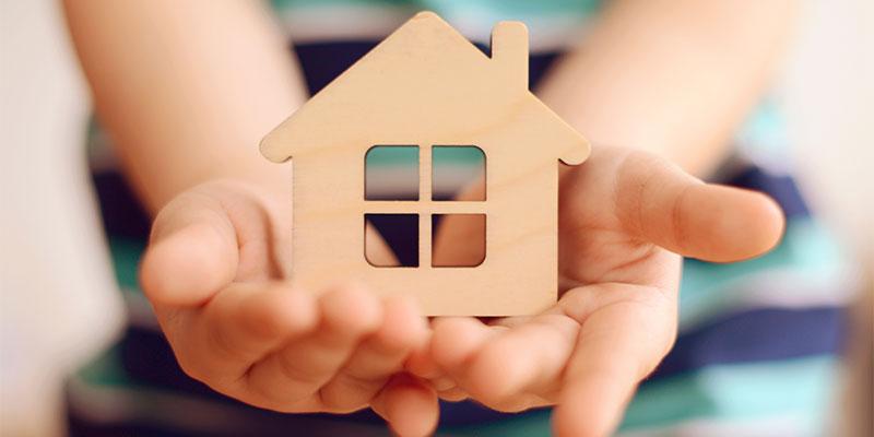 hands holding a wooden toy house 