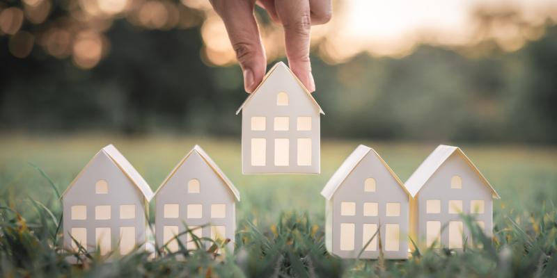 More North Carolinians Eligible for Affordable Mortgage with Down Payment Assistance Paper houses being placed on the grass by a hand above