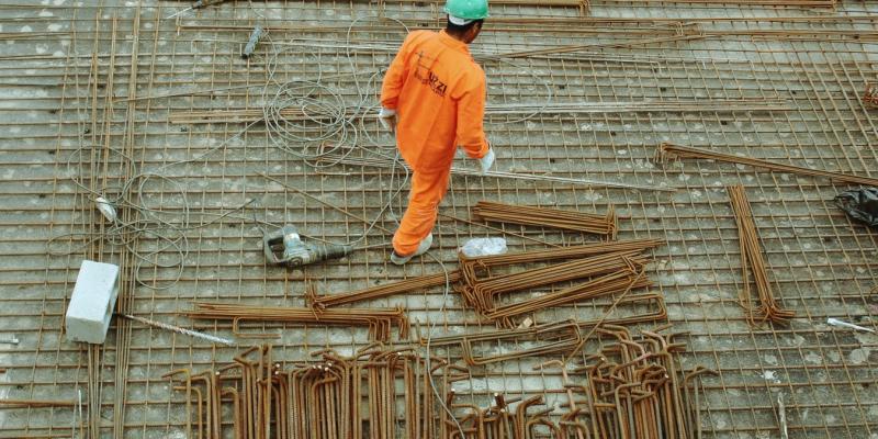 A man in an orange suit walking a construction site