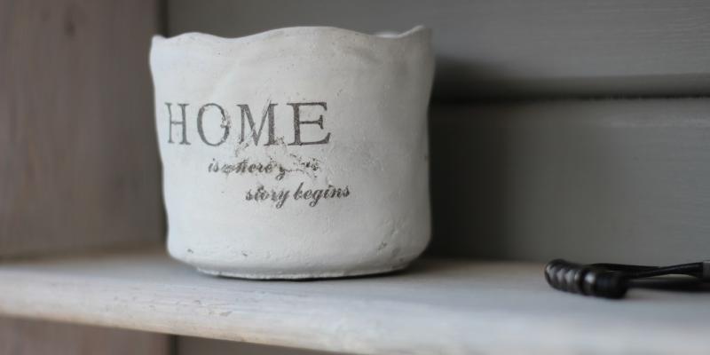 A ceramic vase on a shelf that says HOME on it