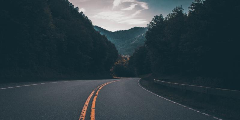 a closeup photo of a road with mountains on either side