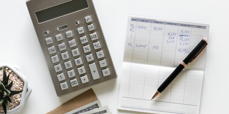 checkbook with pen and calculator on white desk