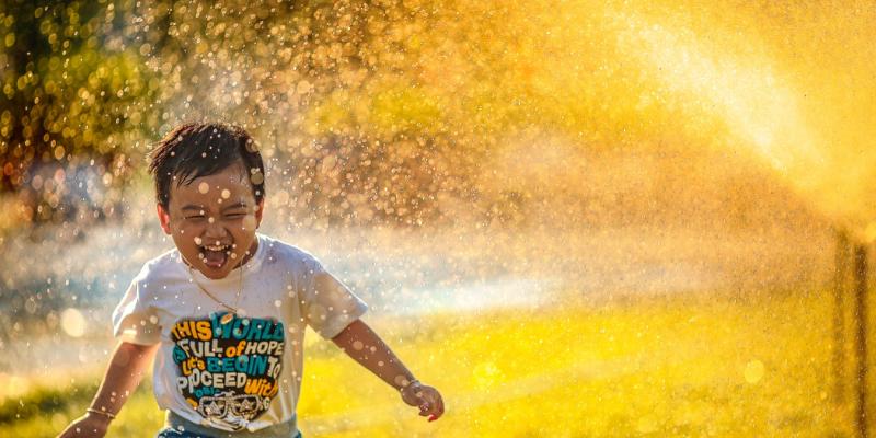 A little boy running through the sprinklers on a sunny day
