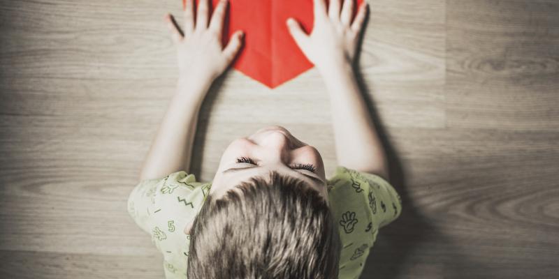 a kid with a red paper heart
