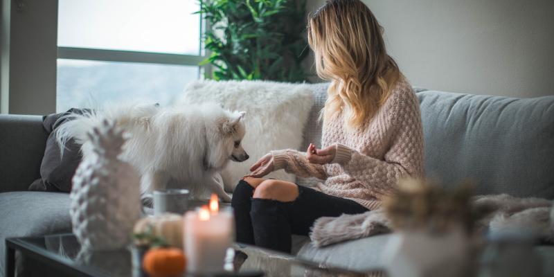 A woman in a sweater in her home with a dog