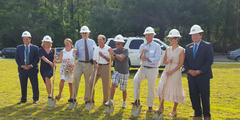 People in hard hats participating in a ground breaking ceremony