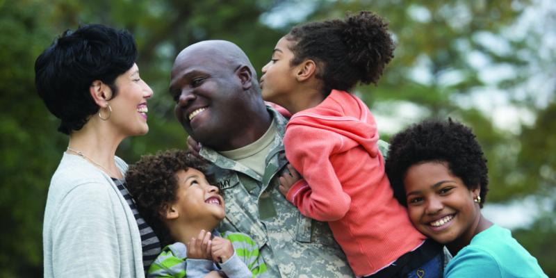 a veteran in uniform hugging his family