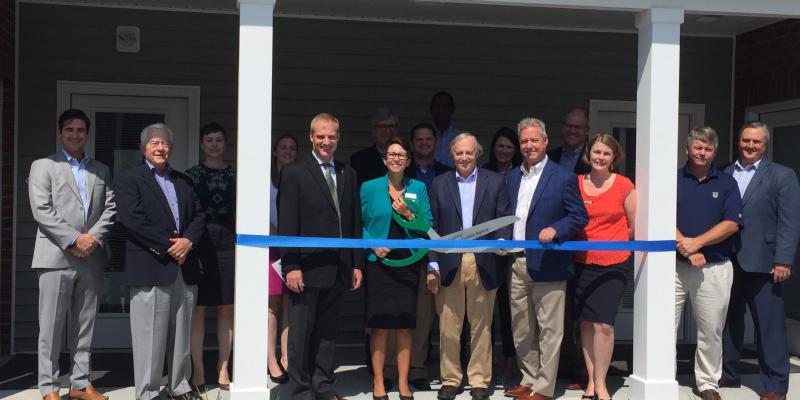 guests lining up to cut the ribbon on the porch of Wakefield Commons apartments