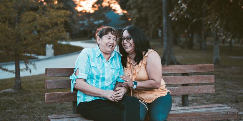 Two women laughing while sitting on a bench