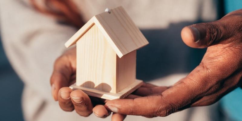 Hands holding a small wooden house