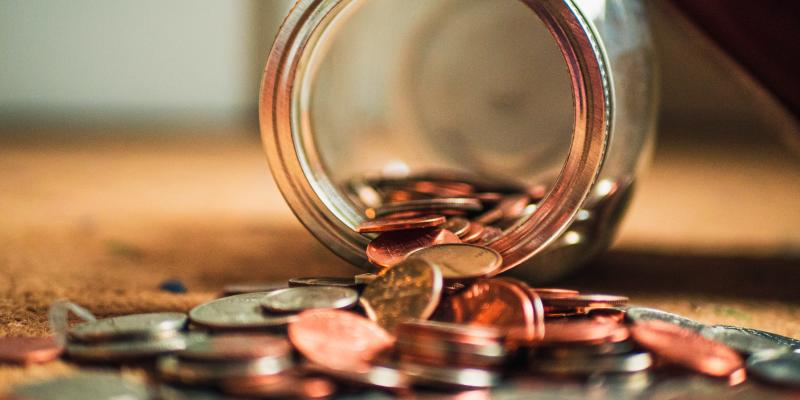 coins falling out of a glass jar onto a table