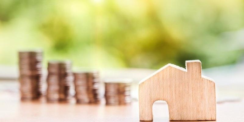 A small wooden house on a table with coins in the background