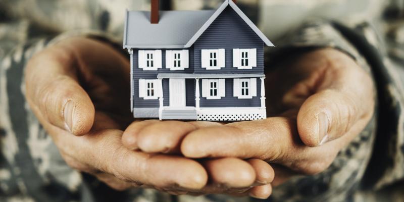 Military person holding a house in their hands